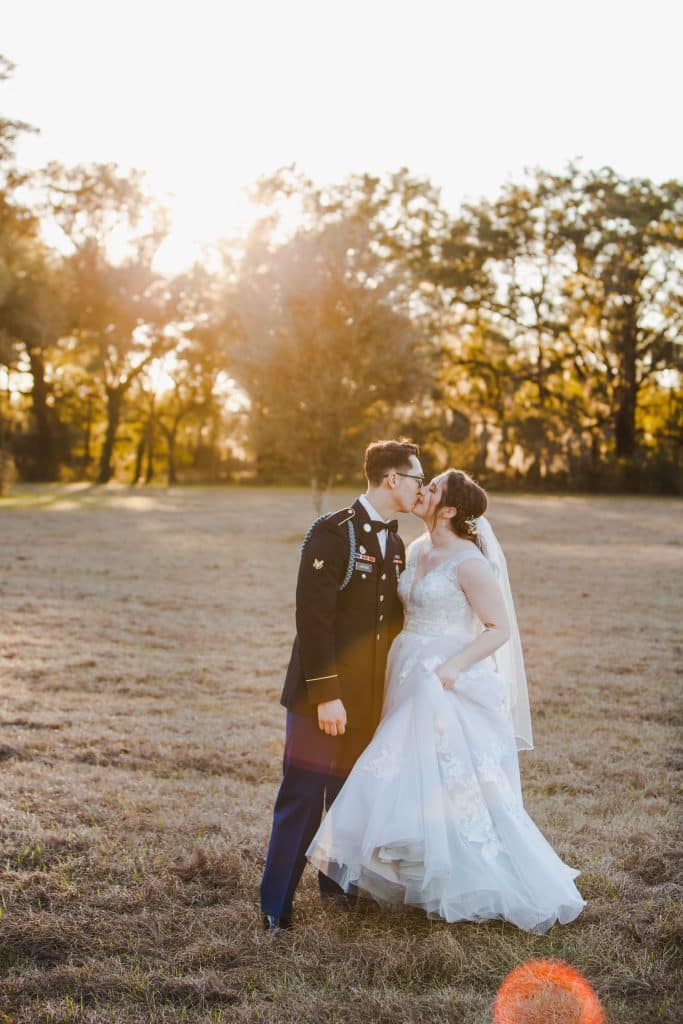 military groom and bride in a field at sunset photographed by Hundreds of Moments Photography