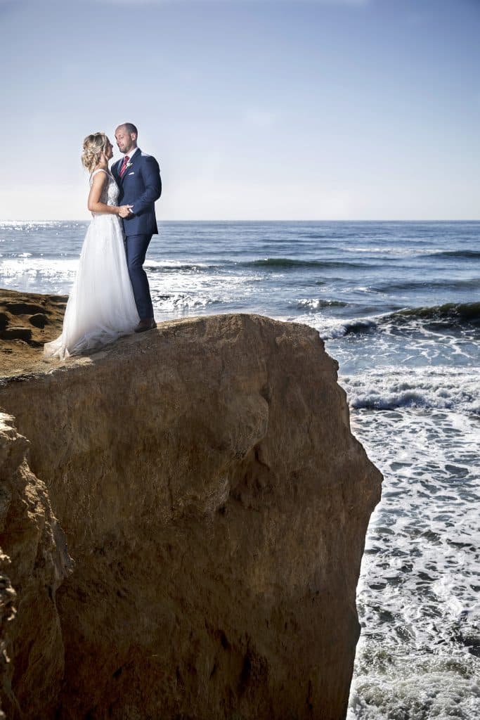 bride and groom on ocean cliff photo by Evan Hampton Photography