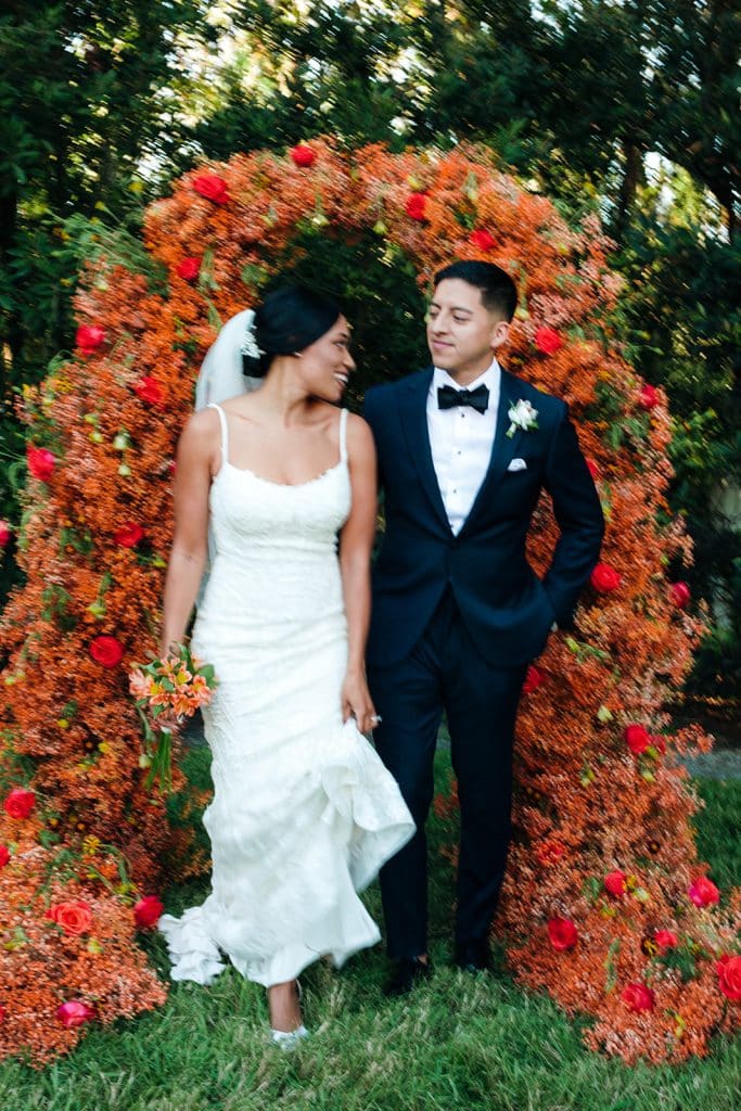 bride and groom walking through floral arch at event coordinated by Celebrations! Weddings & Events