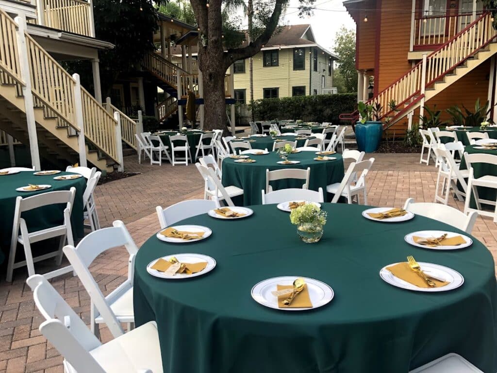 Outdoor patio, white tables and chairs, with green table cloths, mustard napkins, white chargers and small flower arrangements, Central, FL