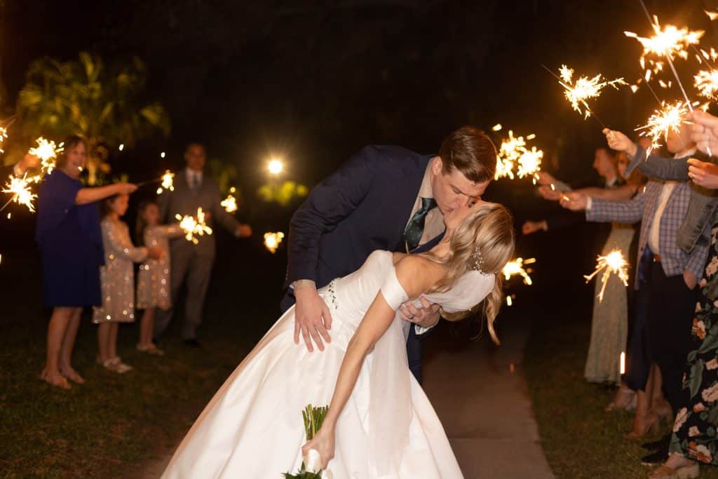 Groom dipping his bride at the receiving line, outdoors, at night, with guests waving sparklers down the aisle, JVK Photography, Central FL