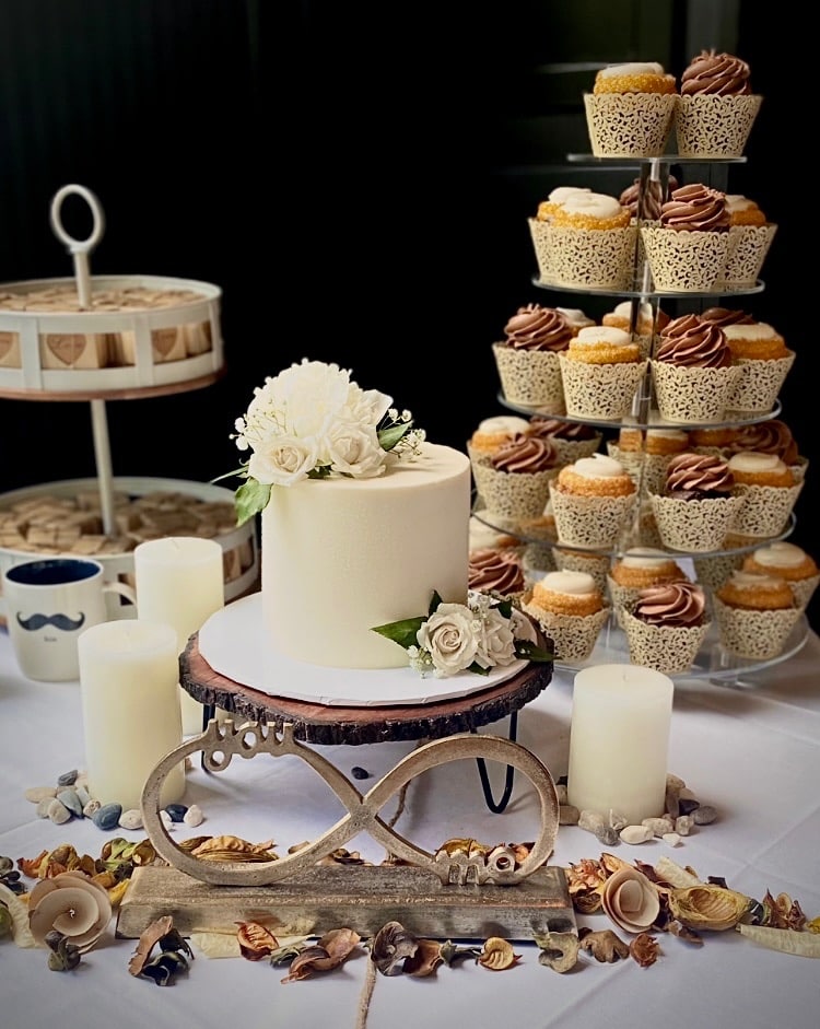 In the foreground, a one tiered white cake, surrounded by white candles and five tiered cupcake tower to the right, other desserts to the left, Central, FL