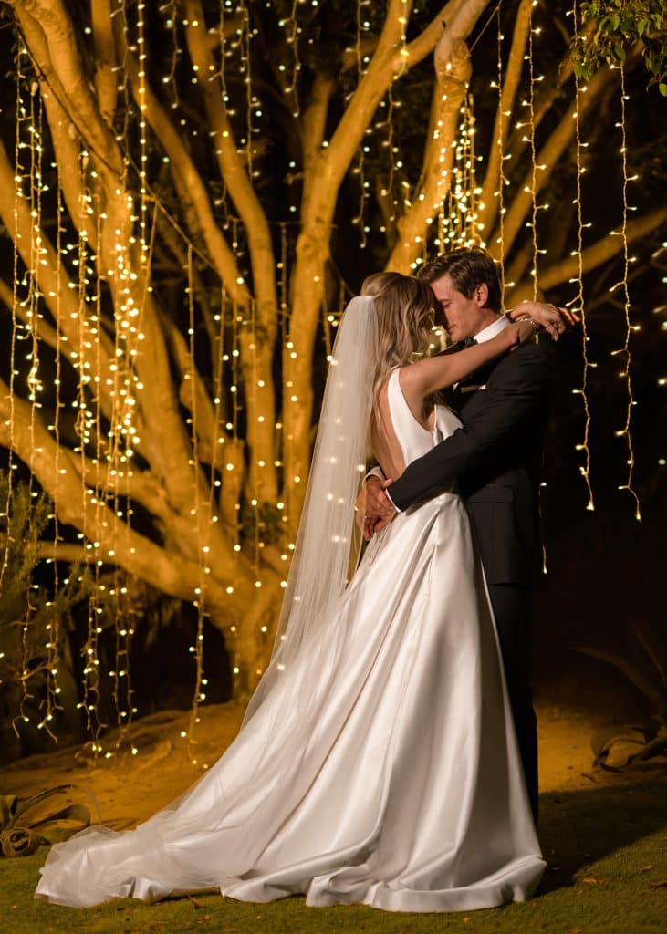 Couple in sweet embrace, under a tree with soft string lights draped down the branches, Orlando, FL