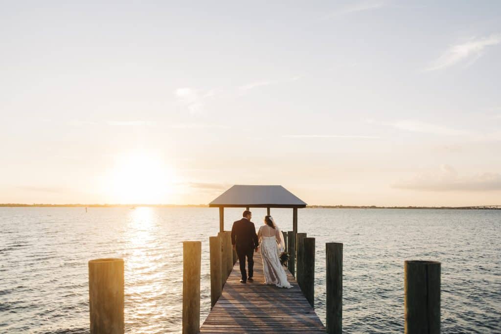 Bride and Groom walking out on a dock at the water's edge, at sunset, Alicia Photography, Central