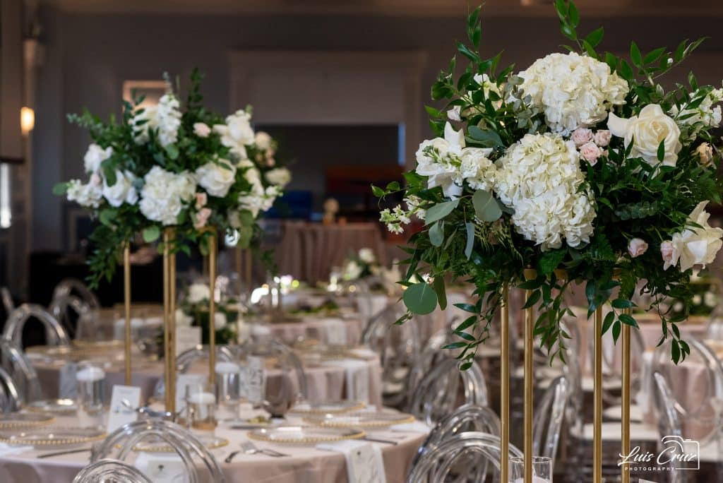 Tall flower centerpieces with white flowers on tables with clear glassware