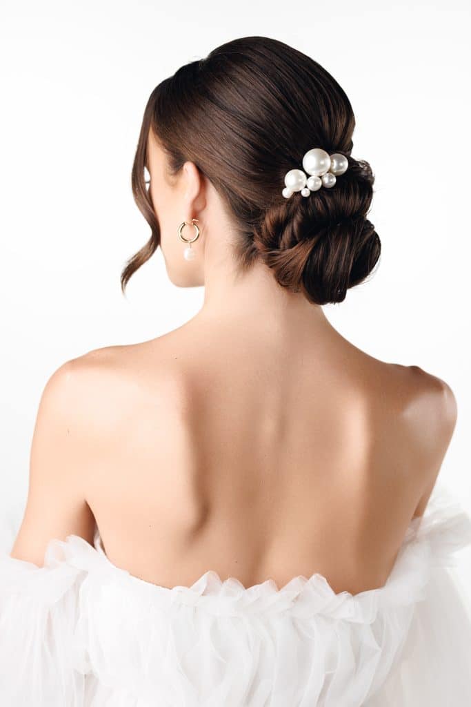 Low bun, close to the neck with a barrette of pearls as decoration, one section curled to shape her face in front, Haley Finegan Hair and Make Up, Central FL
