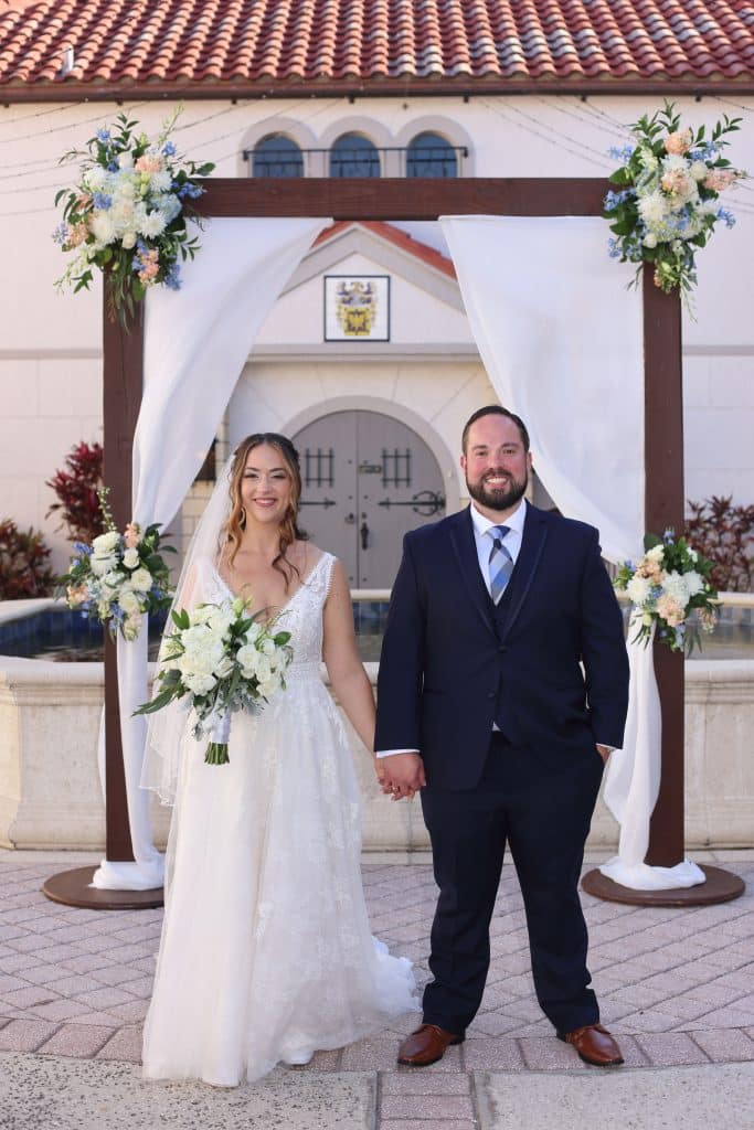 Couple standing under the alter, outside their reception venue, holding hands and posing for the camera, Central FL