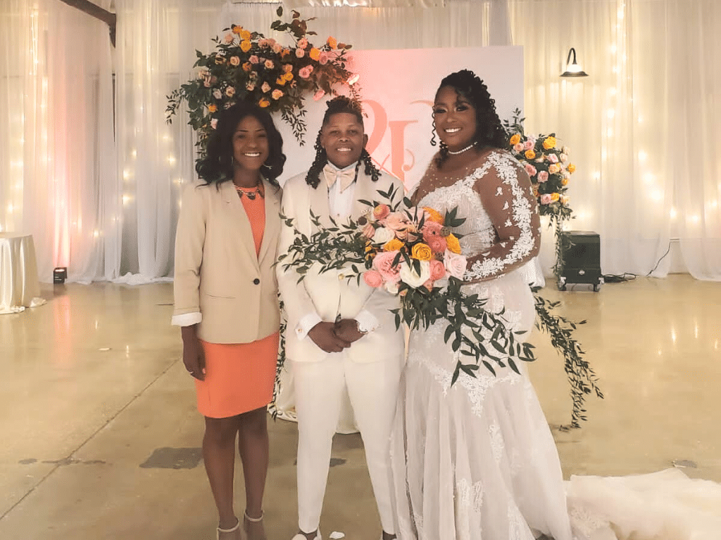 Wedding couple wearing a white suit and white dress, officiant wearing a peach dress and tan blazer at the wedding reception, Marry Me Now Weddings & Elopements, Central FL
