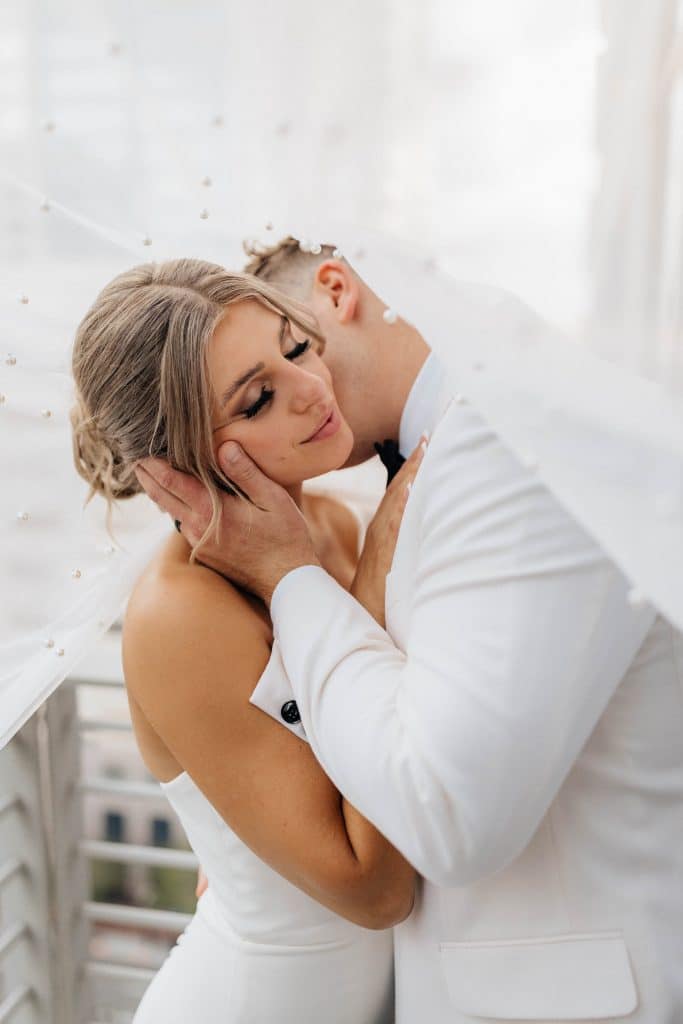Close up of couple on their wedding day on their hotel room balcony, groom kissing his bride on her cheek, Central FL