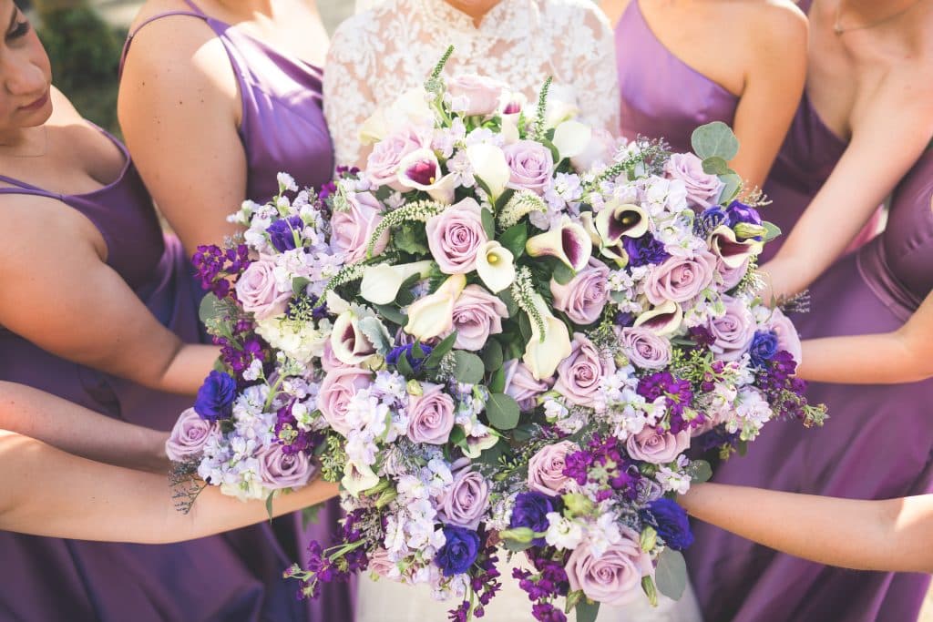 Wedding party all holding their purple and lavender bouquets together in a circle, JF Events and Flowers