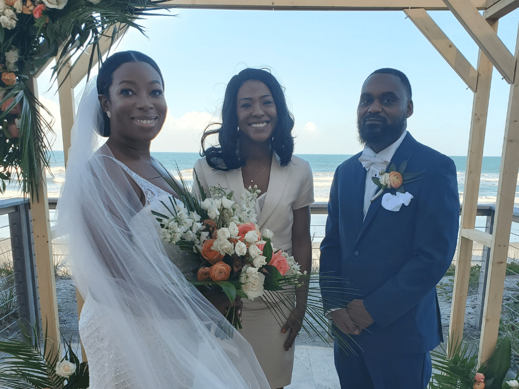 Bride and groom posing for the camera at their altar outdoors with their officiant, by the water, Marry Me Now Weddings & Elopements, Central FL