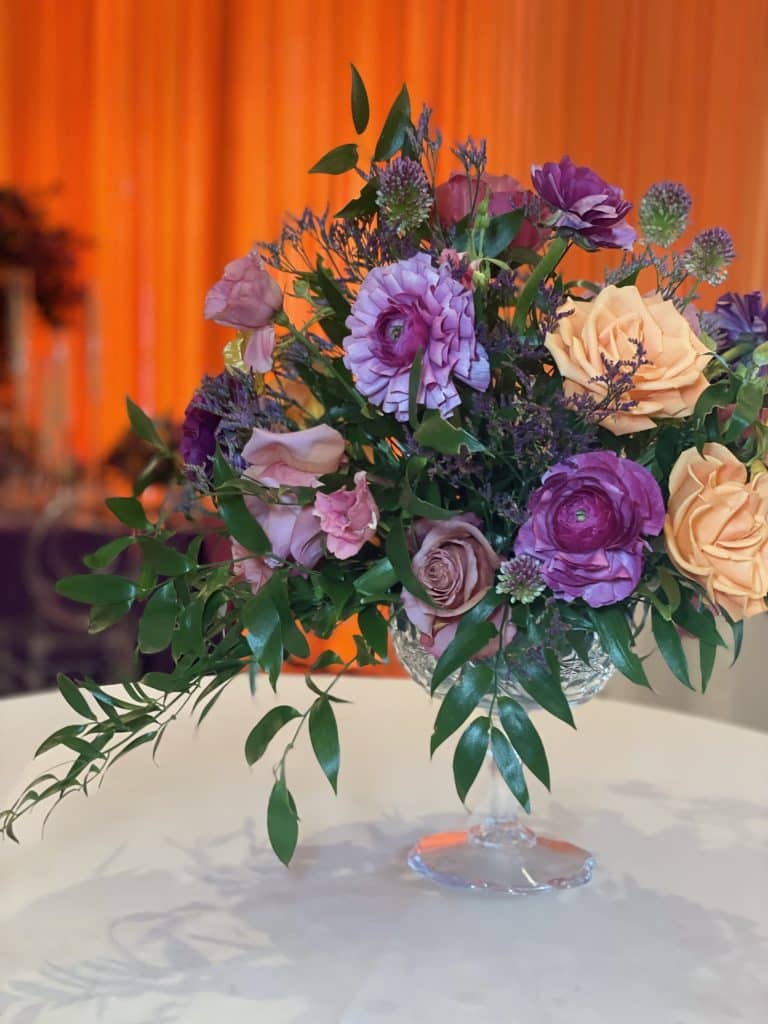 Close up of a purple and peach floral arrangement for a special event, on a white tablecloth, Central FL