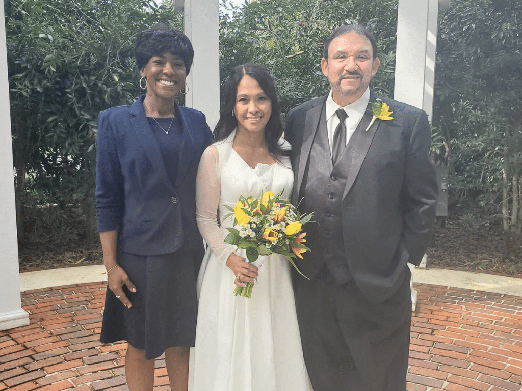 Bride and Groom with the officiant, in a plaza with a brick walkway, with white columns, Central FL