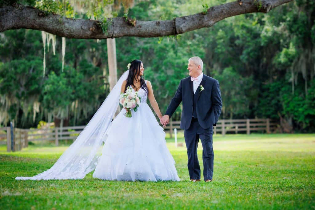 Wedding couple walking on the grass under a tree, while holding hands, outdoors, Uptown Selfies, Central FL