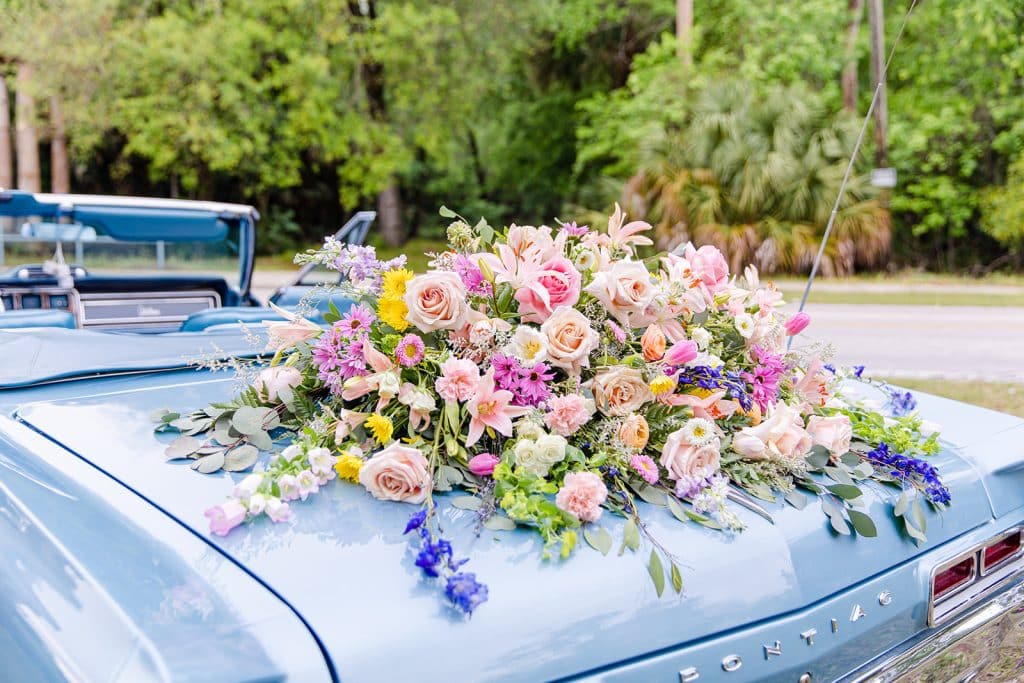 Large floral arrangement of pink flowers, mixed with some yellow and green, on the trunk of a convertible car, Central FL