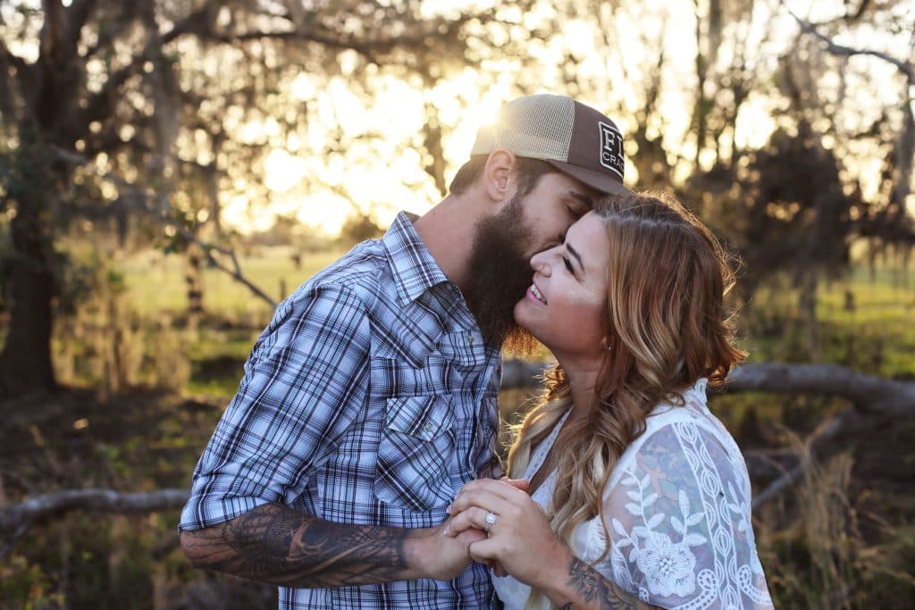 Couple whispering to each other, while embracing each other and holding hands, outdoors on a farm, Central FL