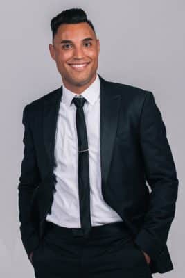 DJ Rey profile photo in a black suit, with white shirt and black tie, Central FL