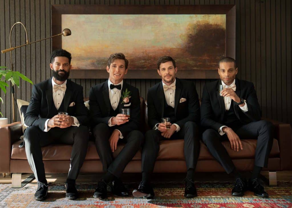 Wedding party, all in tuxes on a brown leather couch enjoying a drink before the wedding, Orlando, FL