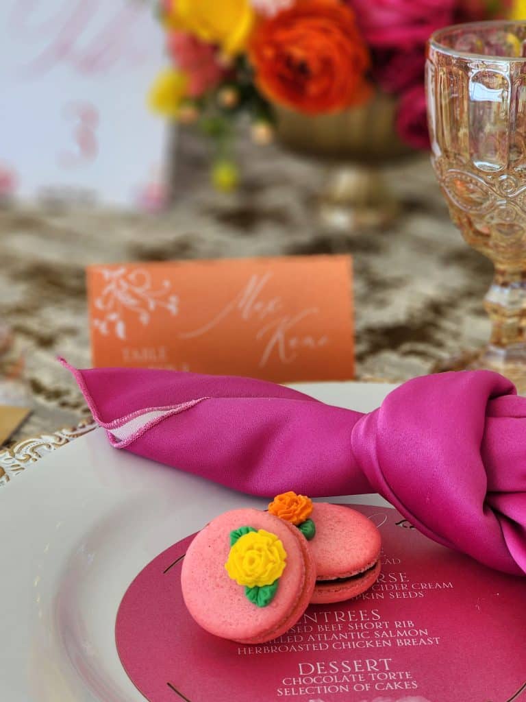 pink macrons with piped flowers on a white plate with a menu card on hot pink paper, bright pink napkin, with a name card in peach, Special Treats by Tanya, Orlando, FL