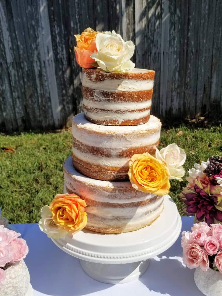 3 layer cake, partially frosted in white, orange, yellow and white flowers on each layer, Orlando, FL