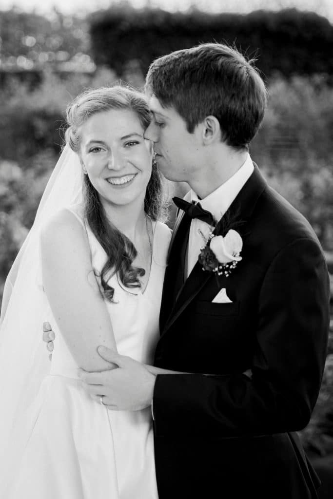 Groom kissing his bride's cheek outdoors on their wedding day, black and white photo, Alicia Frost Photography, Central FL