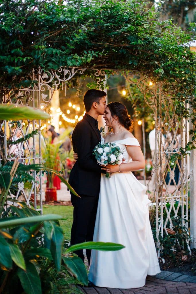 wedding couple stealing a quiet moment at their reception by the entrance/exit with greenery surrounding them, Central FL