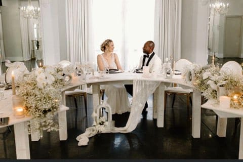 Modern looking head table with white cascading flower arrangements on either end, white votive candles, no tablecloth, LaBellaRose Ballroom, Central FL