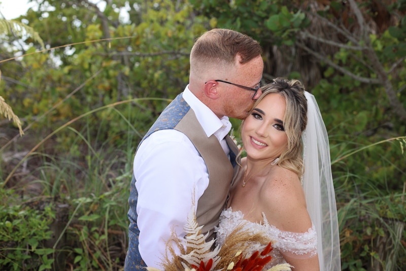 Wedding couple outdoors, groom kissing his wife's cheek, JVK Photography, Central FL