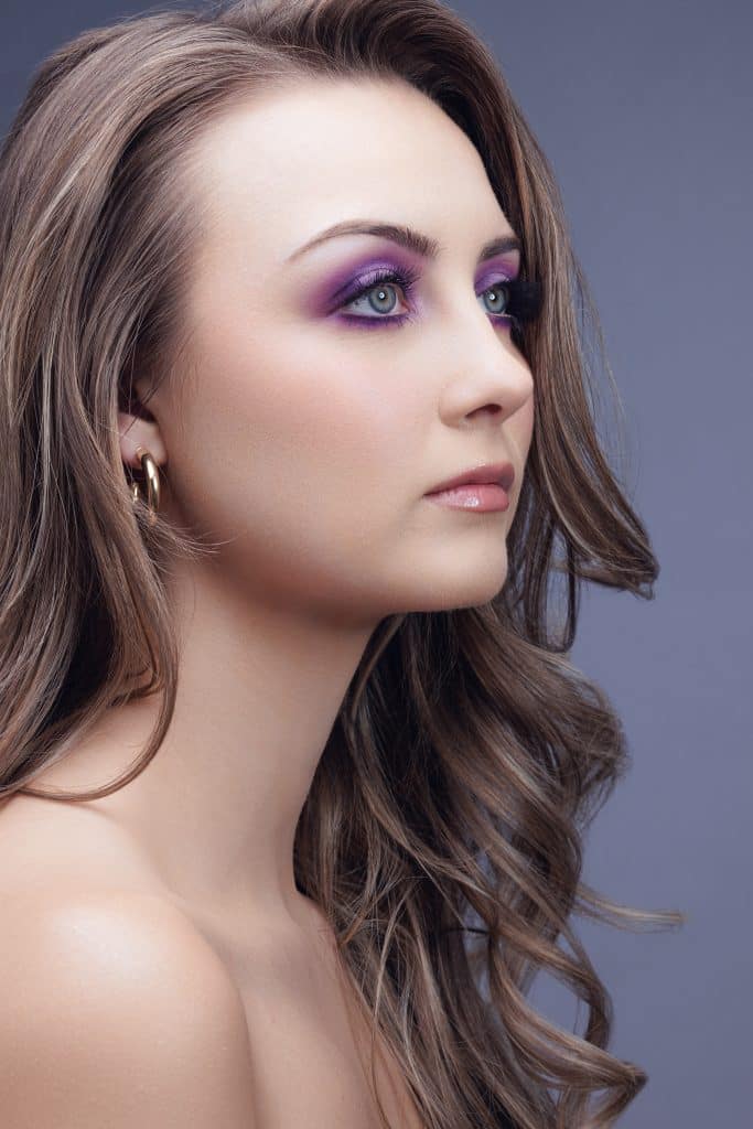 Woman with smoky purple eyes and light makeup, pink lip gloss with her hair worn down with soft curls, Haley Finegan Hair and Make Up, Central FL