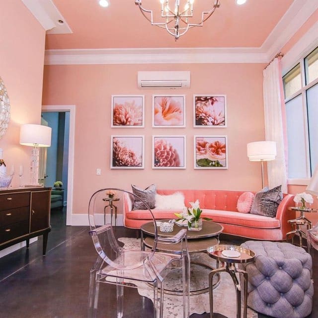Room decorated in pink, with pink walls, pink sofas and antique furniture, tall windows with white sheer curtains, Central FL