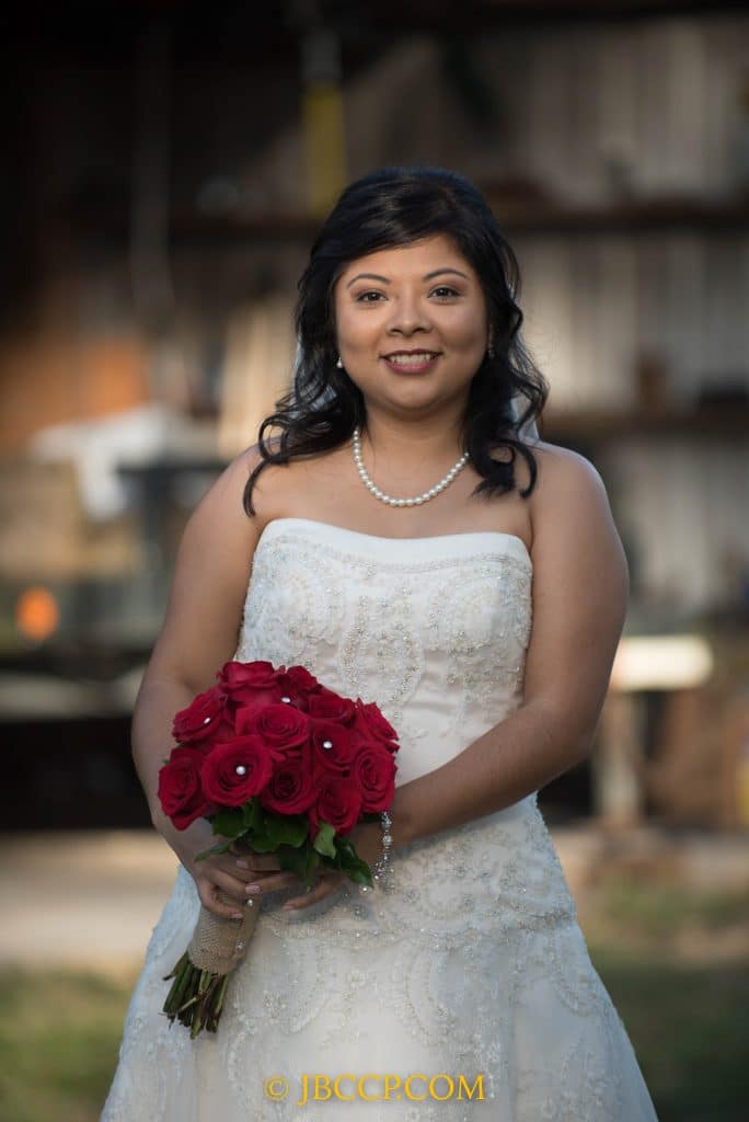 Beautiful bride in a white gown with pearls, and a bouquet of red flowers, Central FL