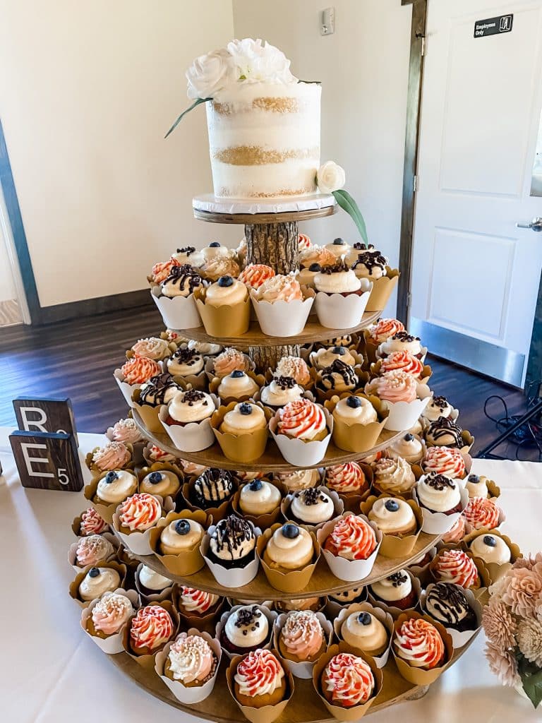 Wood themed tiered tower of a variety of cupcakes, topped with a since layer white cake, flower on top, scrabble letters on the table, Central, FL
