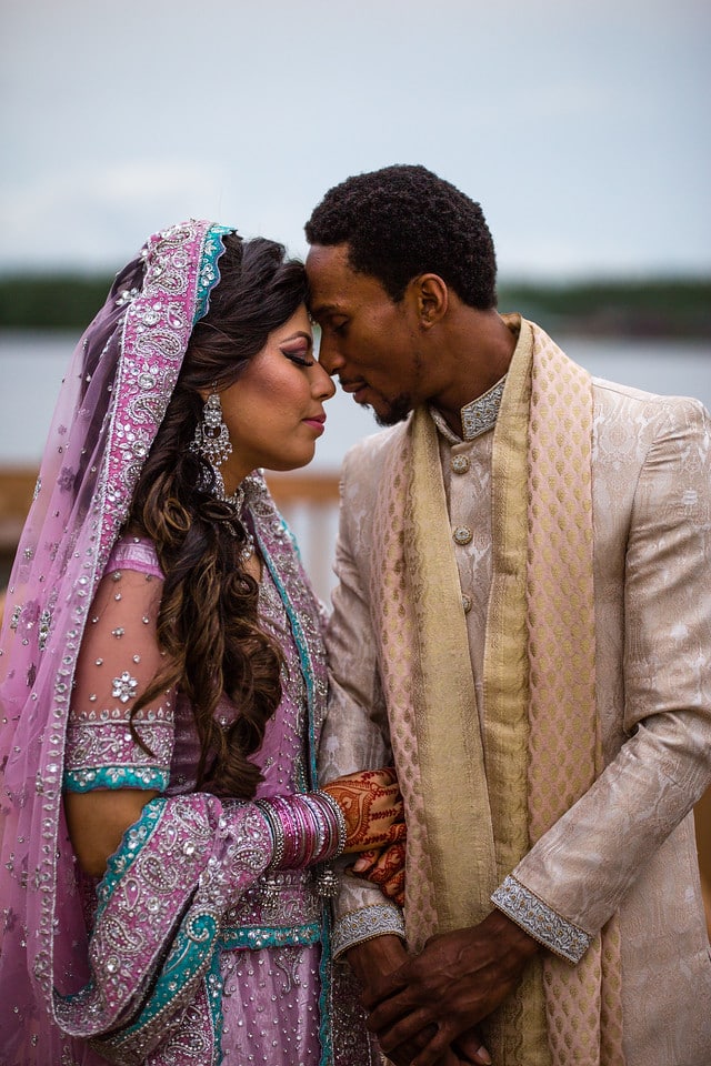 Couple embracing in traditional indian wedding attire, outdoors, near the water, man in tan suit and women in purple and teal dress, Uptown Selfies, Central FL