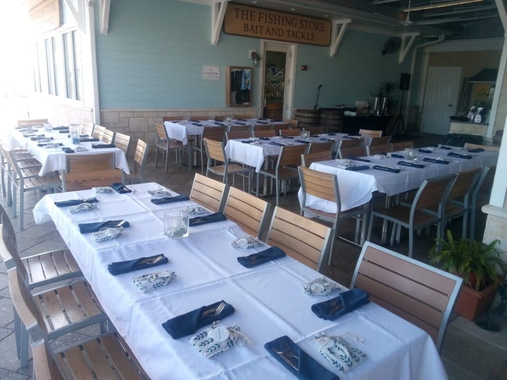Indoor restaurant set up with blue napkins, white tale cloths, wooden chairs, Central FL, Outriggers Tiki Bar & Grille
