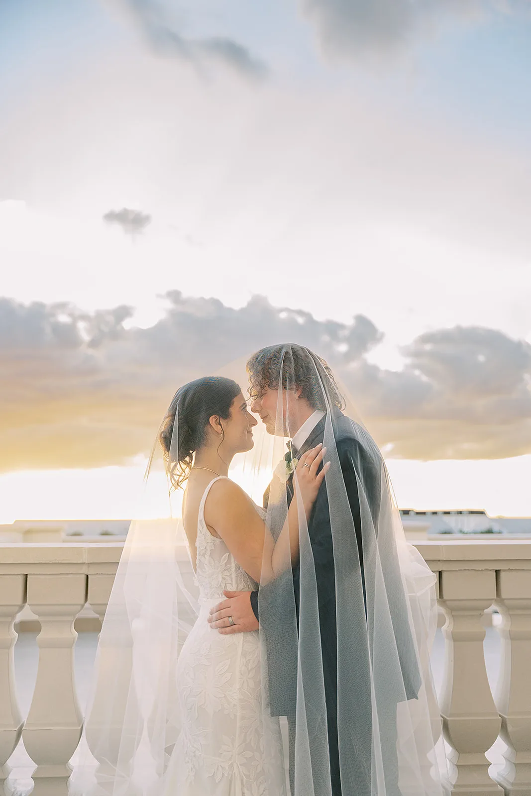 Bride and groom share a romantic sunset moment under the wedding veil on the balcony at World Equestrian Center in Ocala, Florida, with a golden sky backdrop
