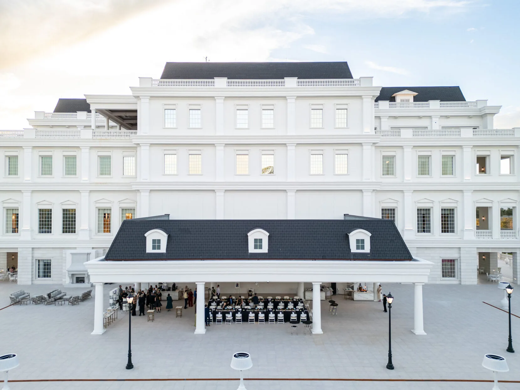 Aerial view of an elegant outdoor wedding reception held under a covered pavilion at World Equestrian Center in Ocala Florida, featuring white neoclassical architecture and black roof details at a luxury Central Florida wedding venue