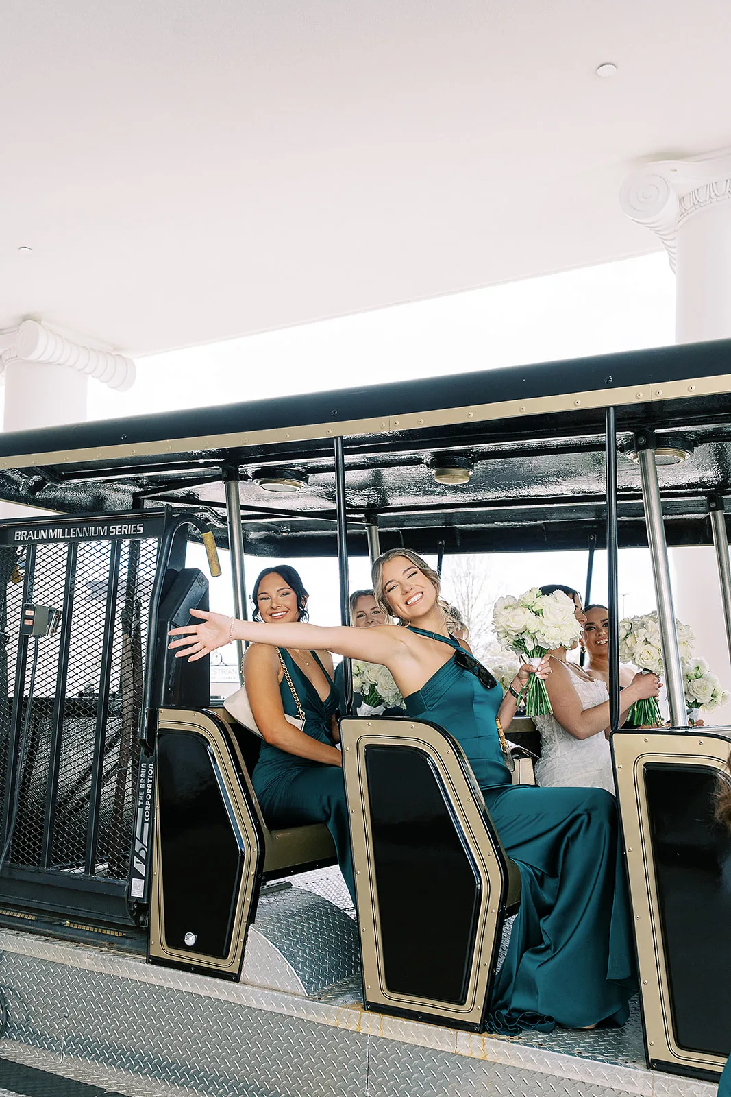 Bridesmaids in emerald green satin gowns riding a Braun Millennium Series trolley with white floral bouquets at World Equestrian Center wedding venue in Ocala Florida