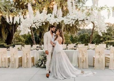 Bride and groom in front of their reception set up and lots of greenery in the background, Orlando, FL