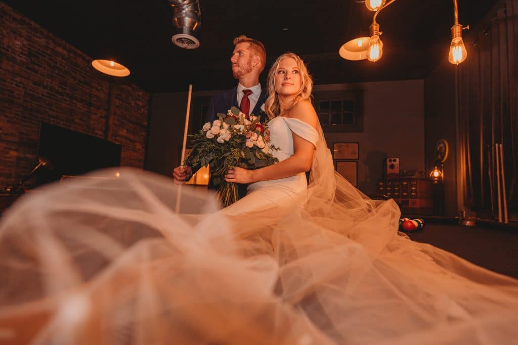 Bride and Groom looking into the distance while her train floats in the foreground of the photo, Central FL