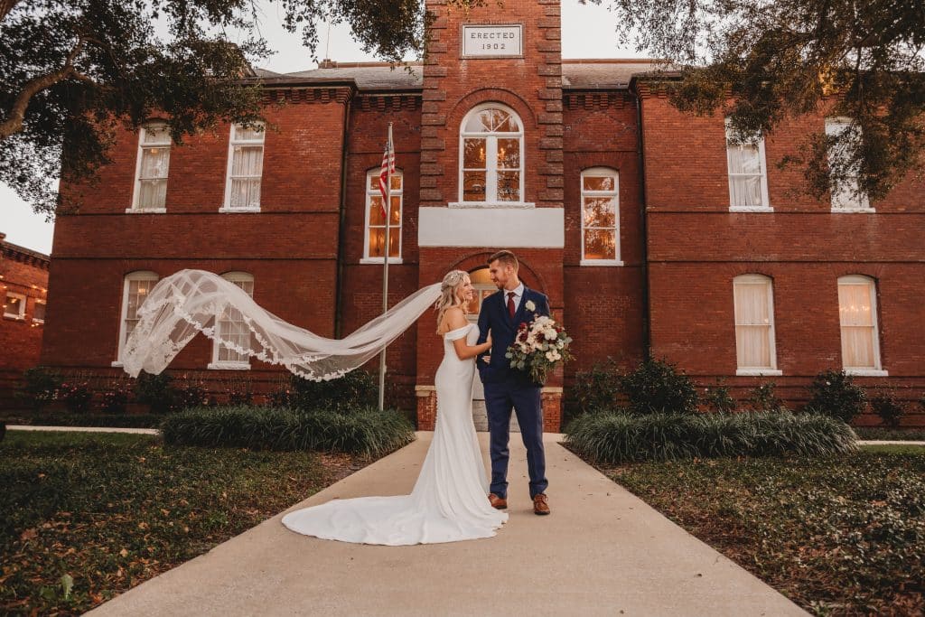 Wedding Couple posing outside, bride's veil blowing in the breeze, Ashley Krug Photography, Central FL