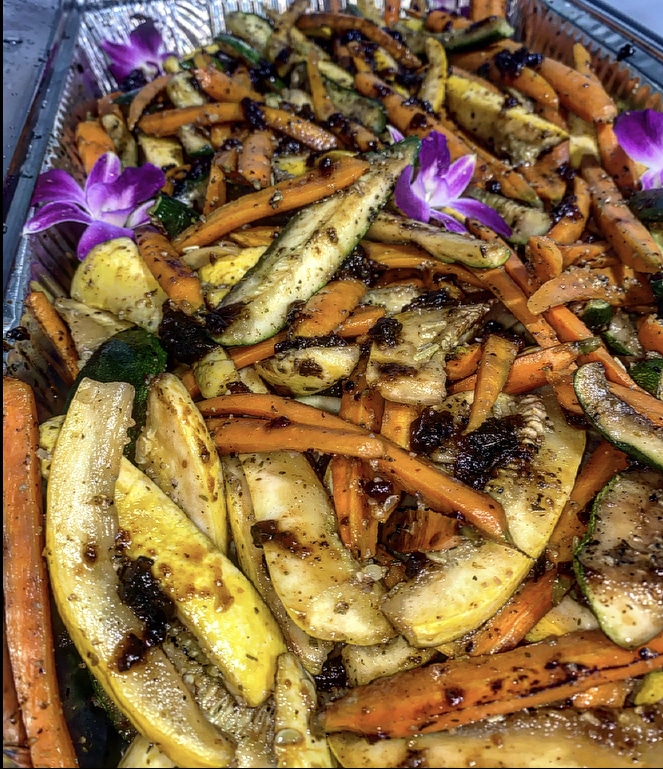 Grilled vegetables, including carrots, squash and zucchini in a large roasting pan adorned with edible flowers, Central FL