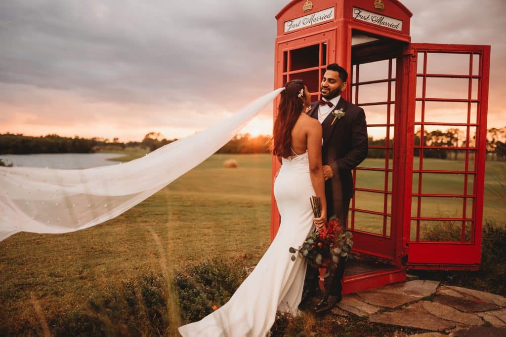 London style phone booth in a field, wedding couple standing in front of it, at sunset, Central FL