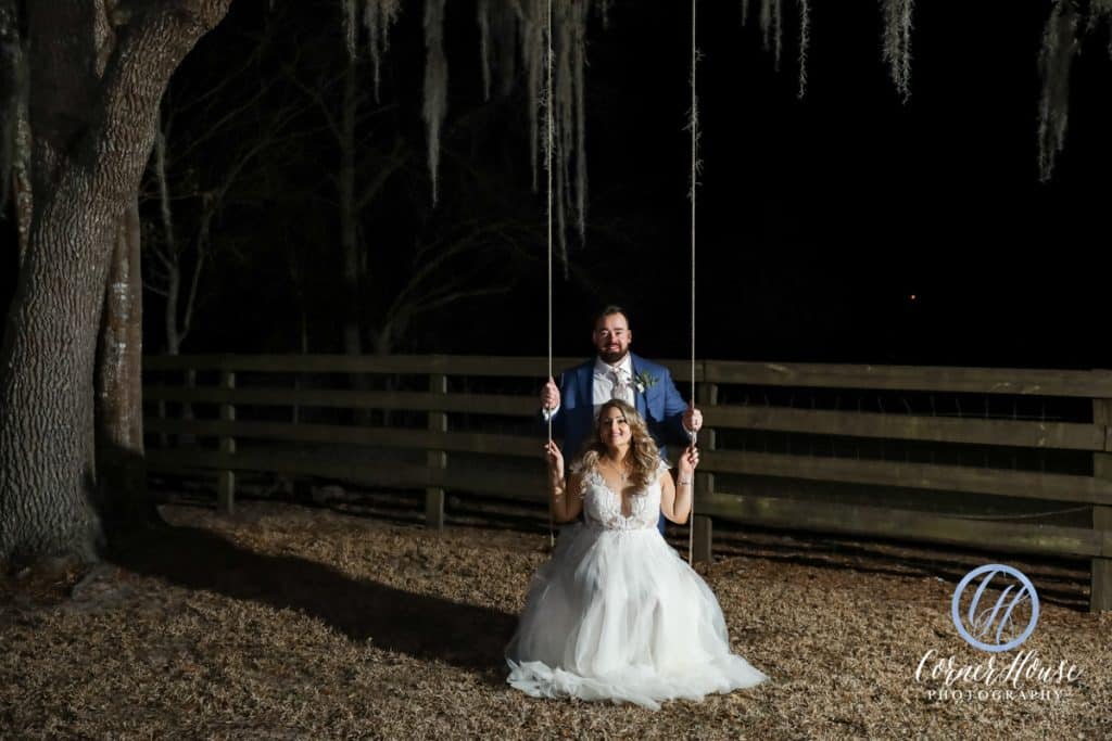 Bride and groom swinging on a tree swing at night on the ranch, Orlando, FL