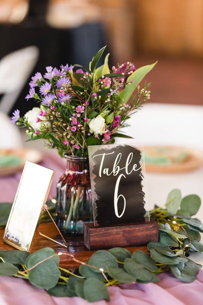 Centerpiece at the reception, table sign, lemon leaves around a small vase with purple and pink flowers, Orlando, FL