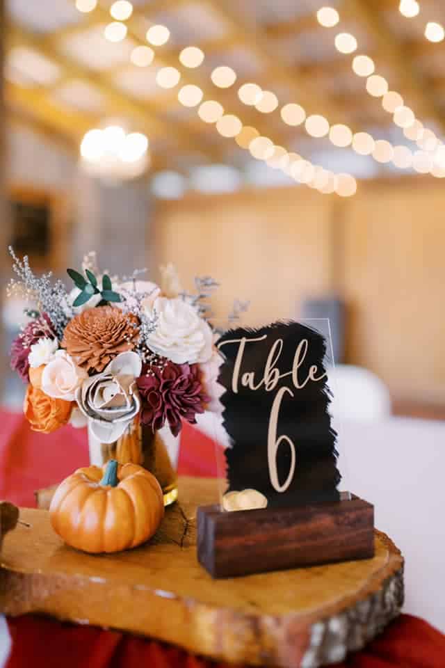Fall themed centerpiece with a wooden table number holder, orange, pink and red flowers, and a small pumpkin, Orlando, FL