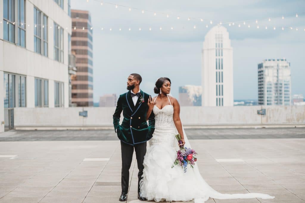 Wedding couple linking arms on a city roof top, skyscrapers in the background, facing opposite directions, Ashley Krug Photography, Central FL