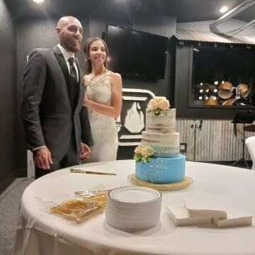 Bride and Groom posing for the camera before they cut into their three tiered wedding cake on the table in front of them, Teri & Co Catering Services, Central FL