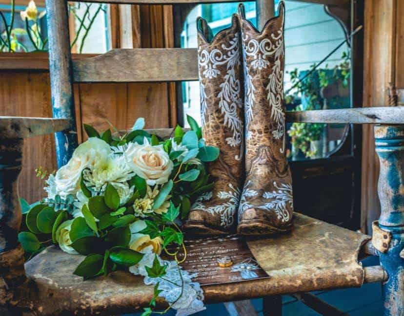 Flatlay of a wedding bouquet and brown cowboy boots, on a wooden chair, Peacock Ranch Wedding Venue, Orlando, FL