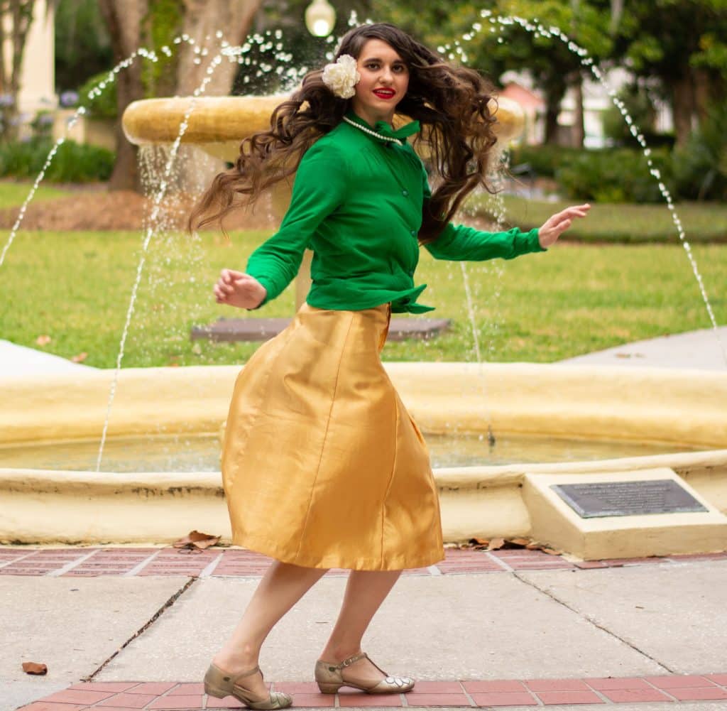 Woman in green and gold costume dancing outdoors in front of a fountain, Vintage Dance Company, Central FL