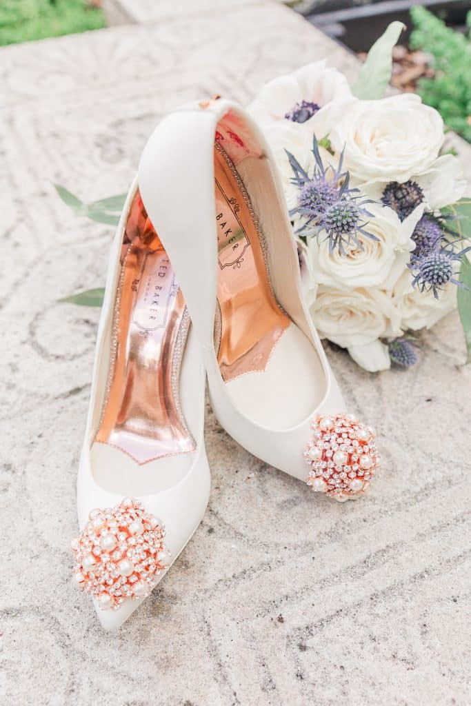 Flaylay of wedding shoes with a white bouquet of flowers on a concrete step